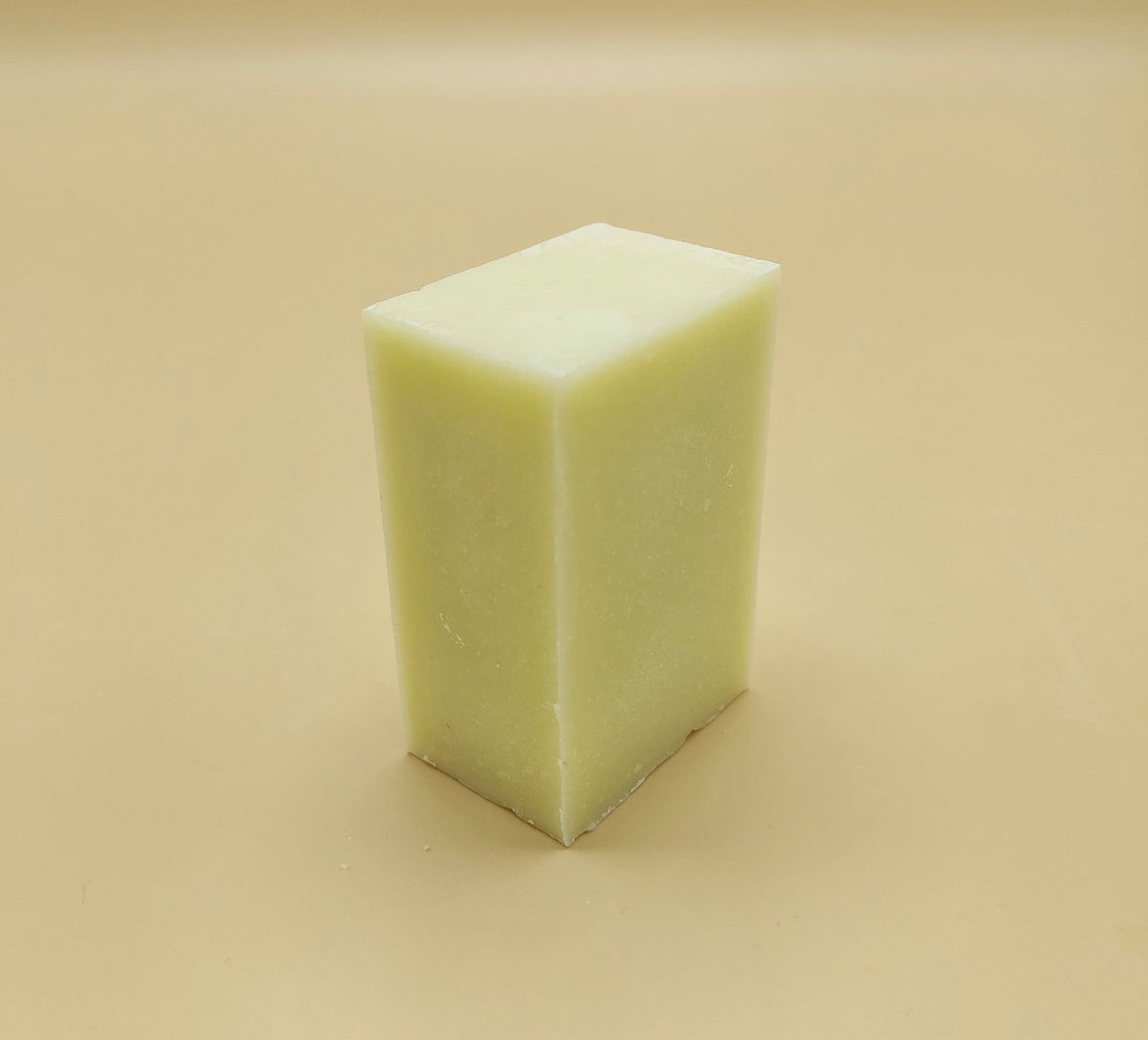 White rectangular bar of soap on a beige background. Organic kitchen dish soap bars offer a sustainable, non-toxic, and cost-effective alternative to liquid detergent.